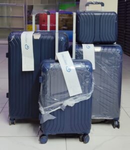 Set of 4 navy blue hard shell suitcases with spinner wheels, including carry-on and travel bag.