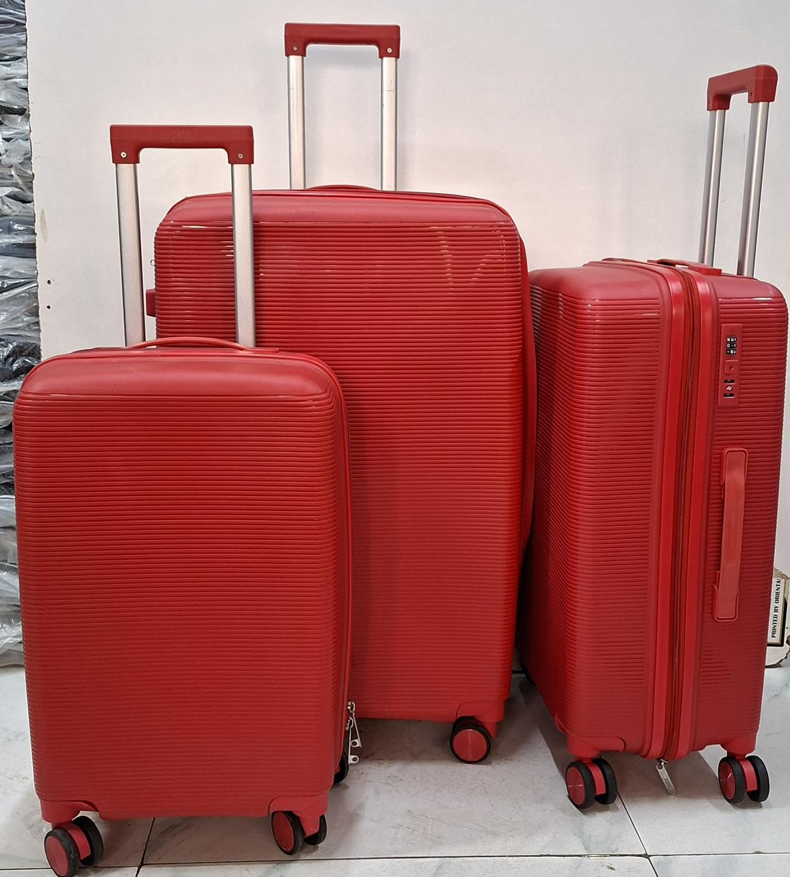 Three red hard-shell rolling suitcases of different sizes with telescopic handles