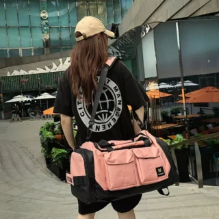 Stylish pink and black duffel bag with multiple front pockets, shoulder strap, and top handles – ideal for gym, sports, or travel