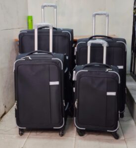 Set of four black expandable suitcases with spinner wheels and telescopic handles.